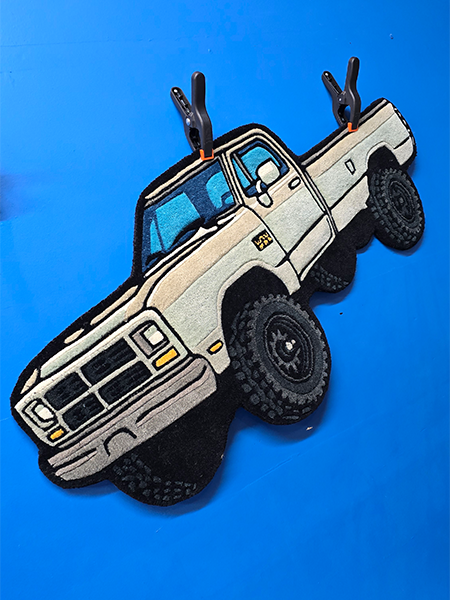 Custom illustrated truck shaped rug hanging on a wall